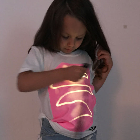 niña con camiseta interactiva blanca y brillo rosa jugando con linterna UV
