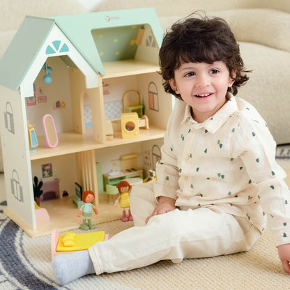 Niño sonriendo mientras juega con la Casa de muñecas Cottage de madera de Classic World