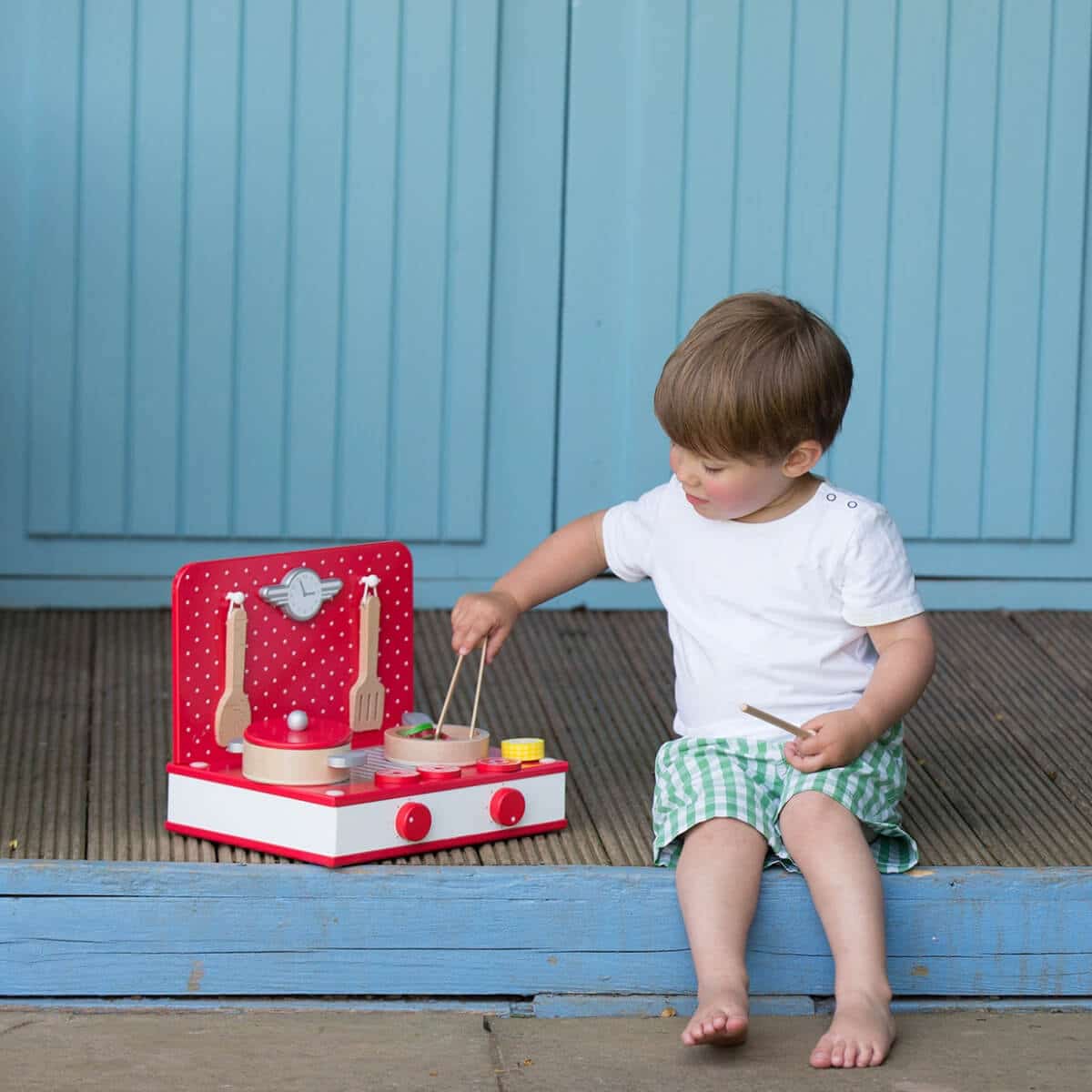 niño jugando con cocina de sobremesa retro de madera roja y blanca Classic World 