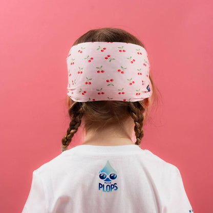 Back view of child wearing light pink cherry pattern headband and white t-shirt with 'Water Plops' logo.