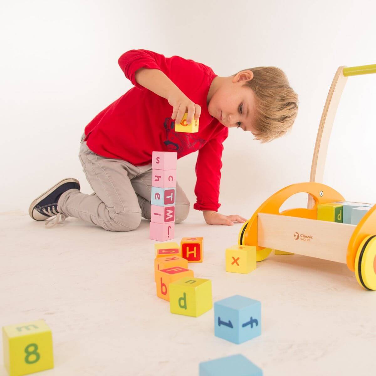 Niño apilando bloques de madera del Correpasillos con bloques de letras y números de Classic World