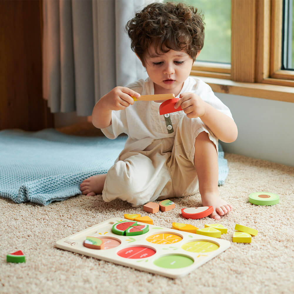Niño jugando a juego simbólico con el Puzzle encajable de frutas con fracciones de madera de Classic World