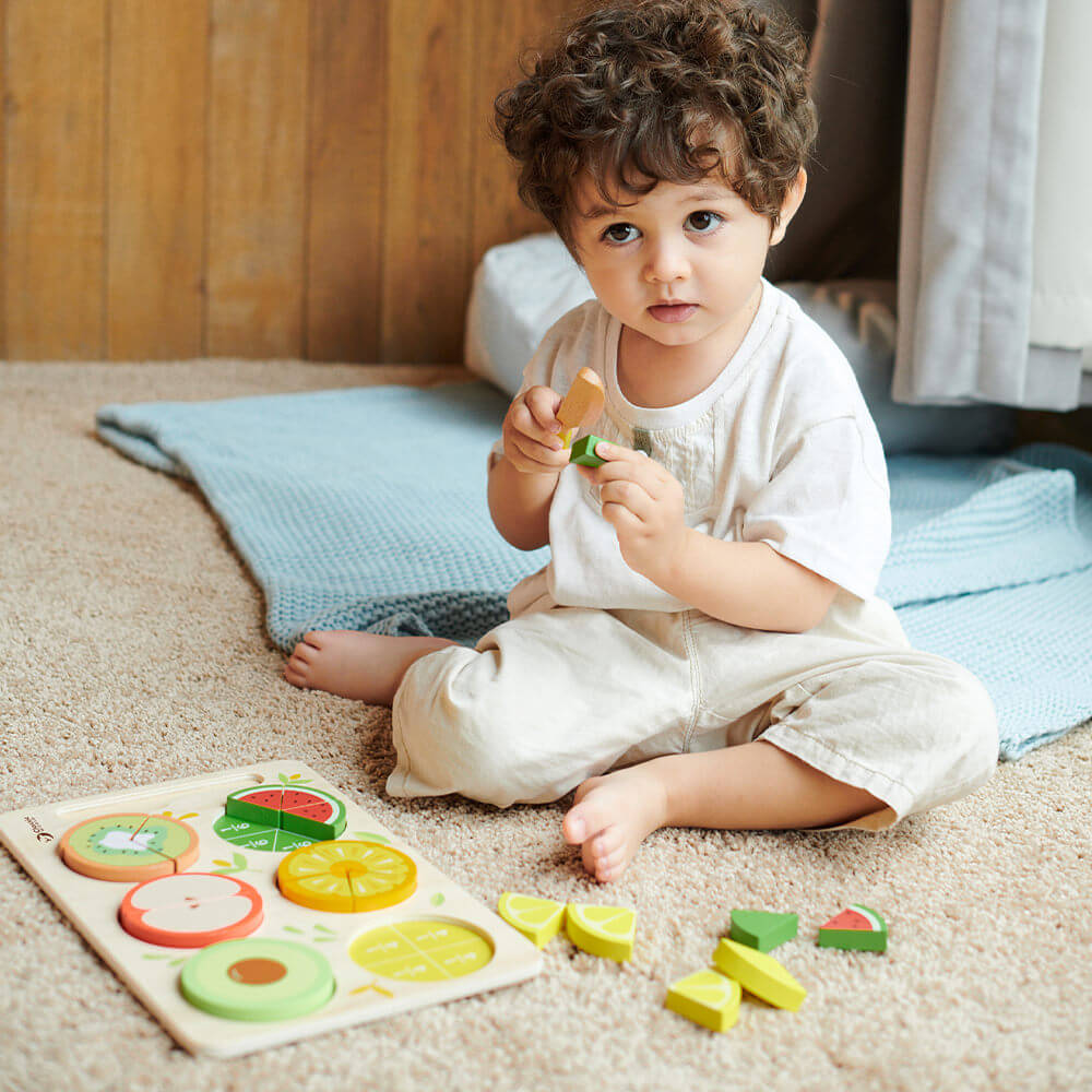 Niño jugando con cuchillo de madera del Puzzle encajable de frutas con fracciones de madera de Classic World