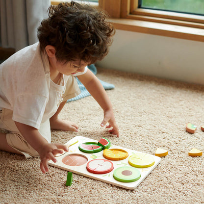 Niño colocando piezas en el Puzzle encajable de frutas con fracciones de madera de Classic World