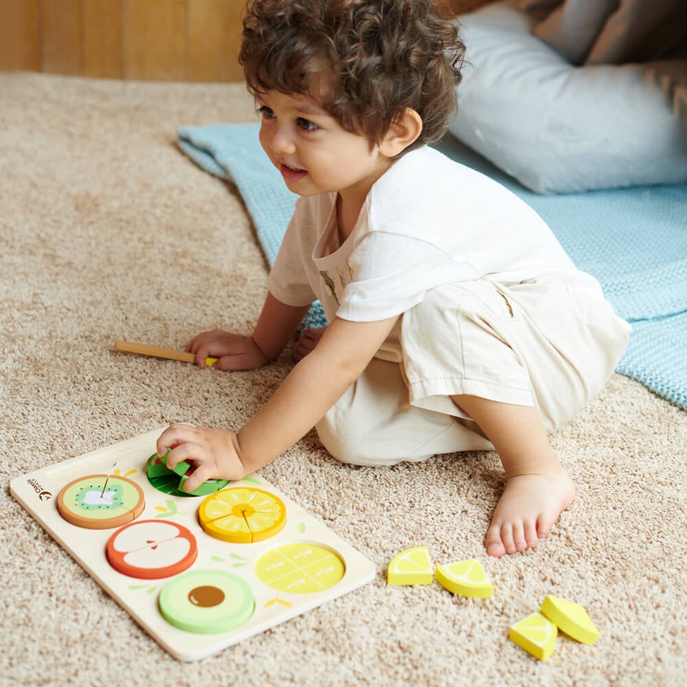 Niño explorando el Puzzle encajable de frutas con fracciones de madera