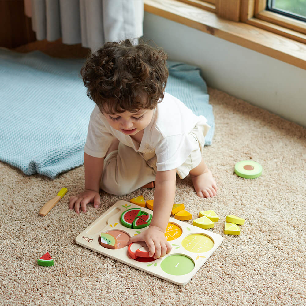Niño colocando piezas en el Puzzle encajable de frutas con fracciones de madera de Classic World