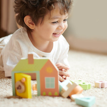 Niño riendo mientras juega con el Juego de ensartar formas con cerradura de Classic World para bebés de 18 meses