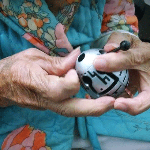 Persona mayor guiando la varita a través del laberinto del huevo Smart Egg