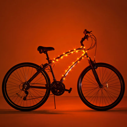 Bicicleta completa con luz LED Brightz en el cuadro encendida sobre fondo naranja