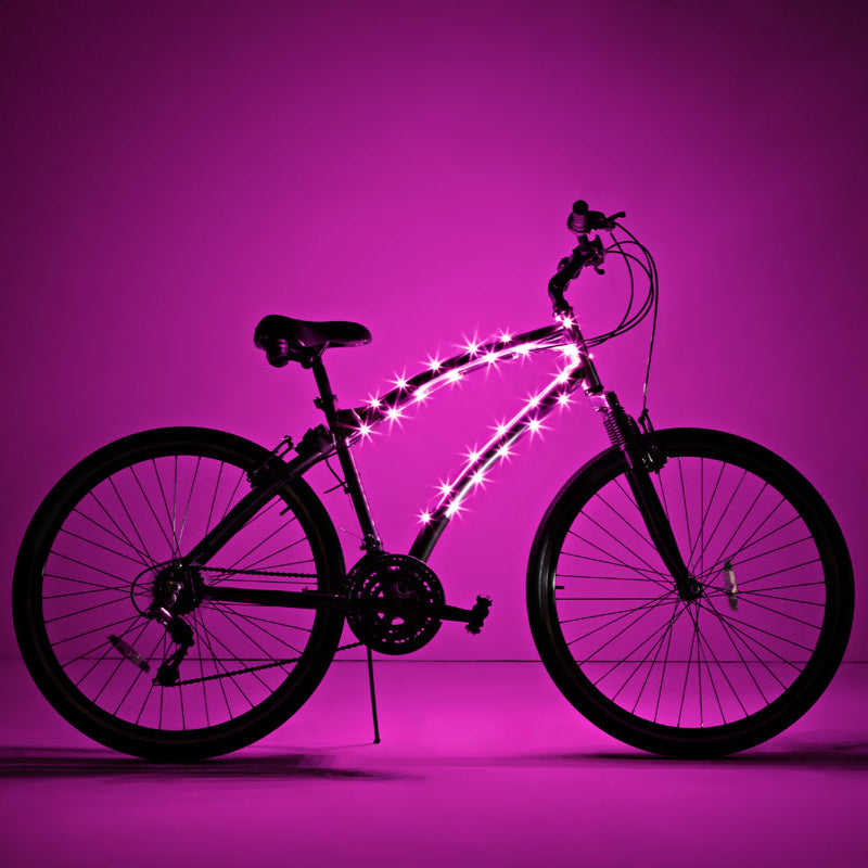 Bicicleta completa con luz LED Brightz en el cuadro encendida sobre fondo rosa
