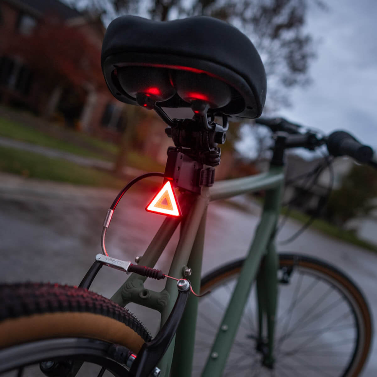 Luz trasera triangular LED Brightz de color roja encendida fijada al sillín de una bicicleta
