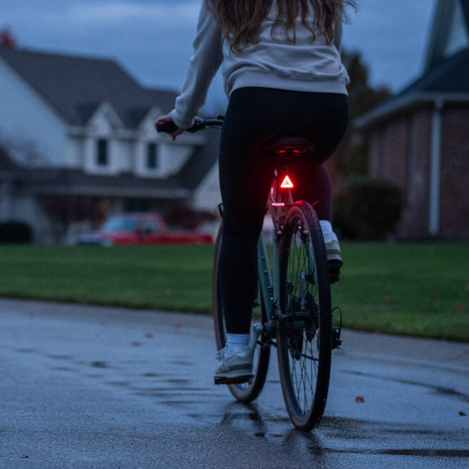 Ciclista con luz trasera Brightz encendida de noche vista desde atrás mostrando visibilidad
