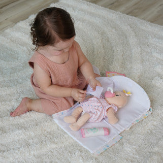 niña cambiando el pañal a muñeca Love Stella sobre el cambiador desplegable
