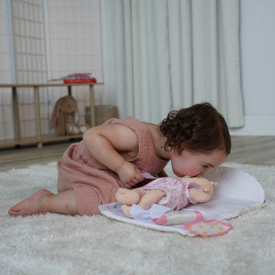 niña jugando a cambiar el pañal a muñeca Love Stella sobre el cambiador desplegable
