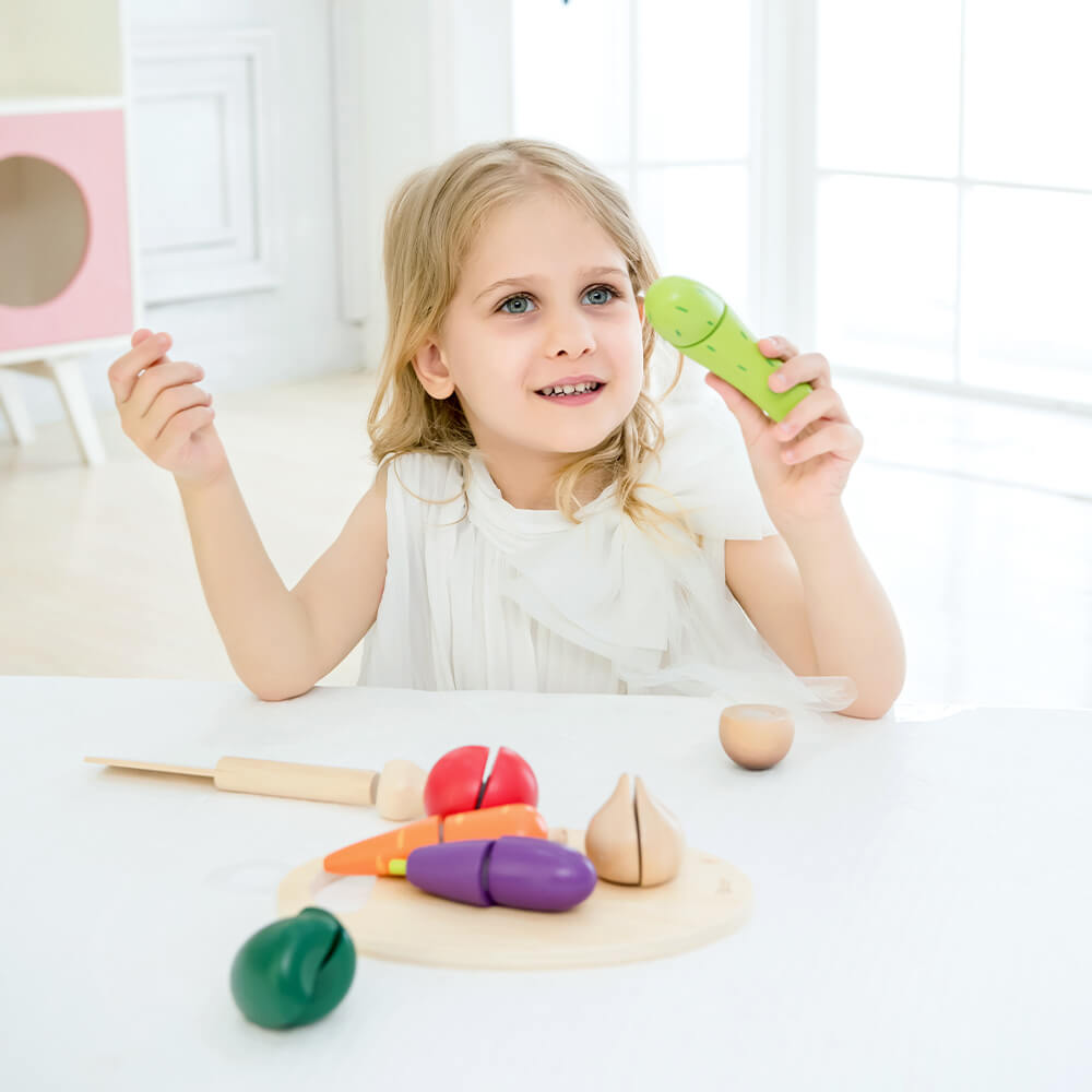 niña con el set de cortar verduras de madera Classic World con tabla cuchillo y siete verduras