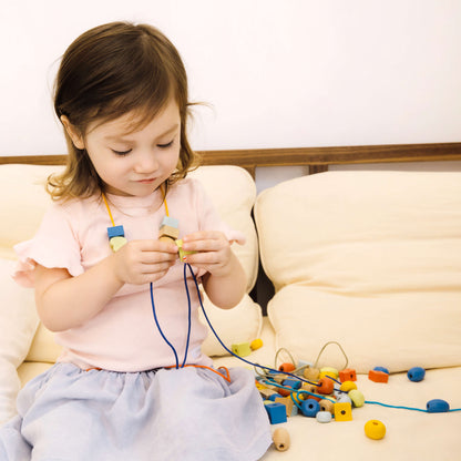 niña desarrollando la motricidad fina con el set de ensartar con cuentas de colores 