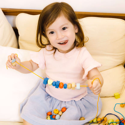 niña mostrando su collar hecho con el set de ensartar con cuentas de colores 