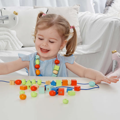 niña jugando con set de ensartar con cuentas de colores 