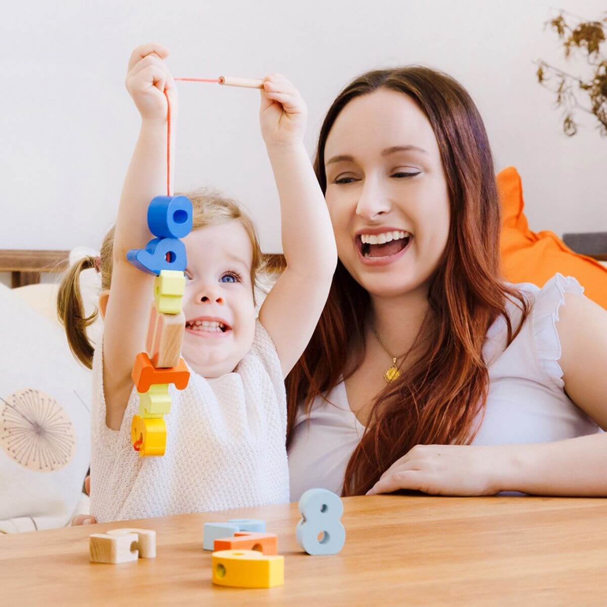 niña jugando con piezas de madera ensartadas en cordón del juego de números Classic World
