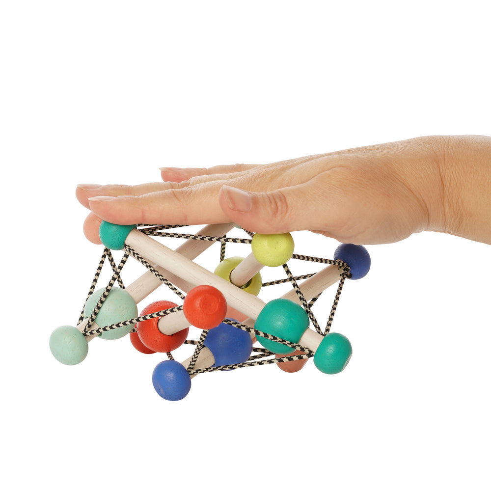 mano aplastando el sonajero flexible Skwish Colorpop de madera