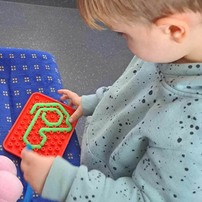 Niño jugando con Juego sensorial de silicona Wiggly Toy rojo 
