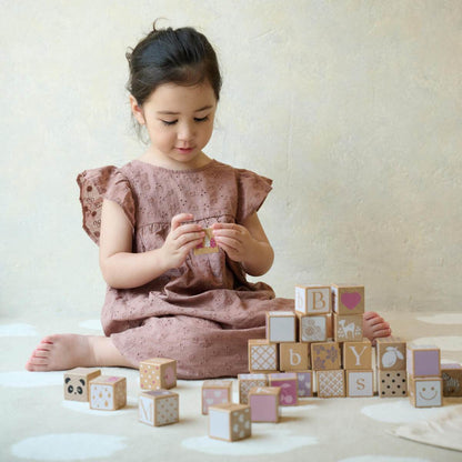 niña jugando con bloques de madera con letras y números Iris Classic World